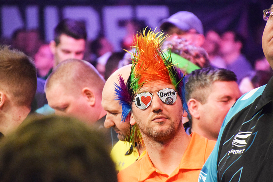 Mann mit einer bunten Perücke auf einem Dart-Turnier